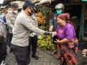 Kapolda Jatim Memakaikan Masker Kepada Masyarakat Saat Pembagian Masker di Pasar Simo